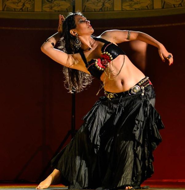 Fusion Bellydance Tänzerin mit Schwarzem Kostüm und rotem Hintergrund
